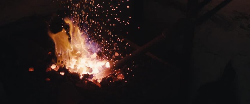 Blacksmith heating iron in fire closeup black dark eerie widescreen cinemascope