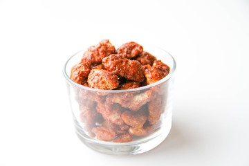 Sugar roasted pecan nuts (caramelized, praline nuts) in a glass on a white background, back view
