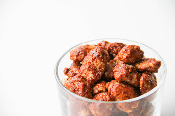 Sugar roasted pecan nuts (caramelized, praline nuts) in a glass on a white background, back view