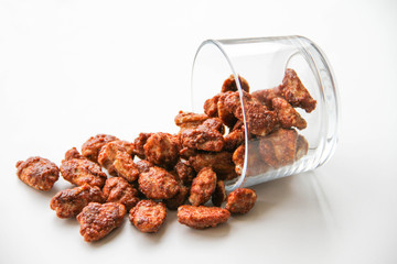 Sugar roasted pecan nuts (caramelized, praline nuts) in a glass on a white background, back view