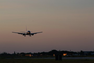 Fototapeta na wymiar Airplane Landing On Runway During Sunset