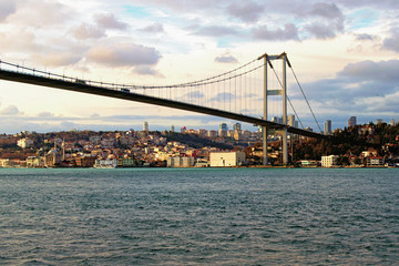 Beautiful landscape view of Bosphorus Bridge (also known as 15 July Martyrs Bridge) over strait. Beylerbeyi district with Beylerbeyi Mosque in the background. Winter sunny day. Istanbul, Turkey