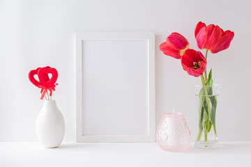 Home interior with decor elements. Mockup with a white frame, red tulips in a vase on a light...