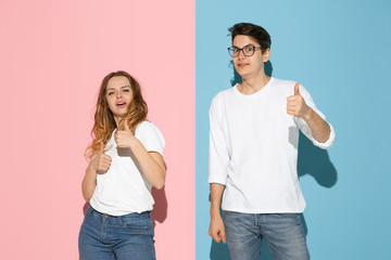 Thumbs up. Dancing. Young and happy man and woman in casual clothes on pink, blue bicolored background. Concept of human emotions, facial expession, relations, ad. Beautiful caucasian couple.