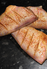 Red perch in a marinade on a black background.
