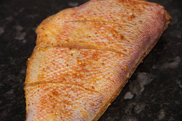 Red perch in a marinade on a black background.