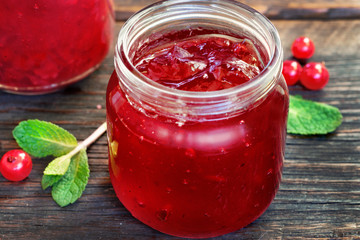 red currany jam in glass jar on wooden table close up