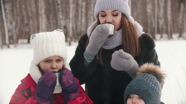 Family drinking hot drinks from the termos near the forest