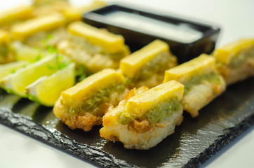 Skinless and boneless battered Alaska Pollock fillet pieces, topped with mushy peas and fried potato