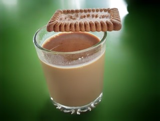 Tea chai and biscuit on green background table In India , Indian masala chai tea or black tea made with various spices and ingredient 