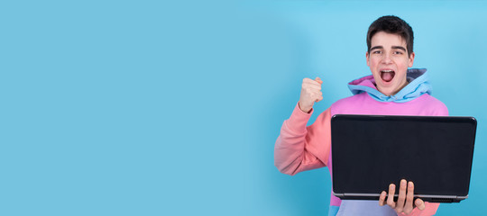 young teenage man or student with laptop isolated on background with surprise or success expression