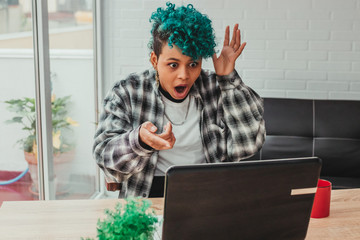 young woman or student girl with computer and expression of amazement or surprise at home or in the office