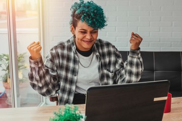 young woman or girl with computer and expression of success or celebration at home or in the office