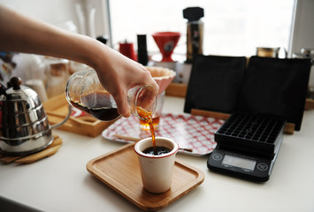 Pouring black filter coffee from decanter into ceramic cup. Manual brewing still life. Third wave specialty aesthetics