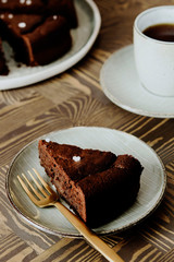 Moist Ginger Chocolate cake sliced and sprinkled with sea salt and cup of tea on wooden table. Selective focus