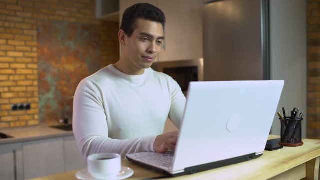Young man typing on laptop, male programmer working at home, freelance project