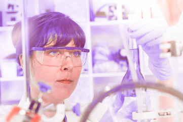 Young female scientist or tech in protective wear holds liquid biological sample, virus or flu...