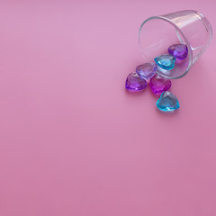 Crystal multicolored hearts scattered on a pink background. Composition for Valentine's Day.