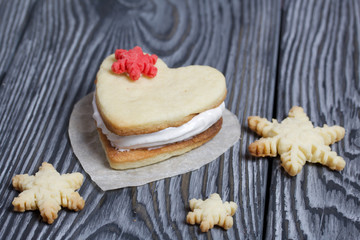 Marshmallow sandwiches decorated with cookies in the shape of a snowflake. On brushed pine boards painted in black and white.