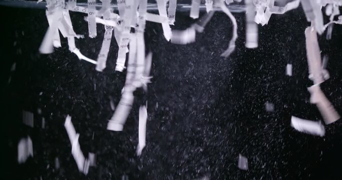 Close up of shredded paper leaving shredder against black