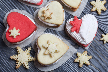 Marshmallow sandwiches decorated with cookies in the shape of a snowflake. On brushed pine boards painted in black and white.