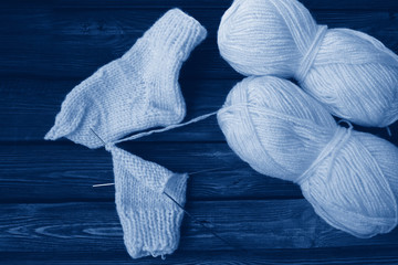 Knitting needles with thread. Tinted photo in classic blue, 2020 trend. Two skeins of thread and a...
