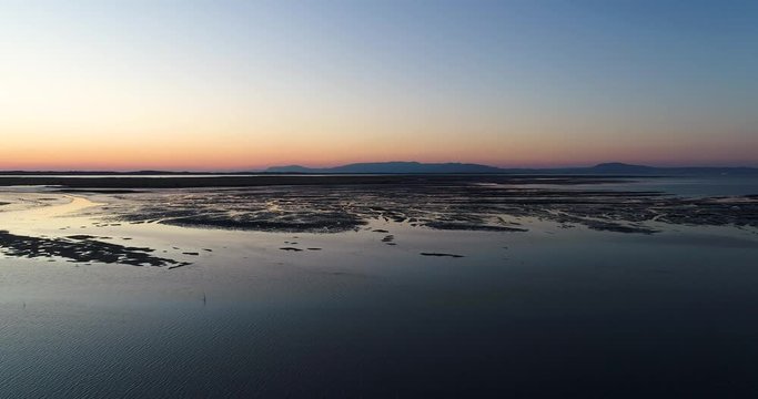 Aerial view of the Sado Estuary near the village of Carrasqueira, with a rice plantation, the Troia Peninsula and the Arrabida Mountain on the background at sunset, in Portugal.