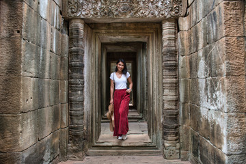 Beautiful, pretty, young Thai girl is exploring the ancient ruins of Angkor Wat (City/Capital of Temples) Hindu temple complex in Siem Reap, Cambodia. The largest religious monument in the world