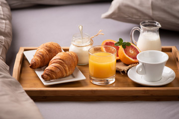 Continental breakfast. Breakfast tray on bed with coffee, orange juice and croissant