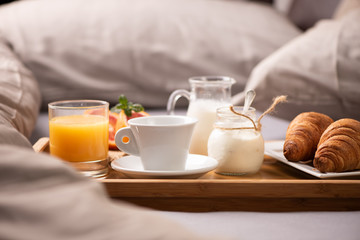Fototapeta na wymiar Continental breakfast. Breakfast tray on bed with coffee, orange juice and croissant