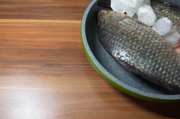 On the table lies a fresh, river fish with ice.