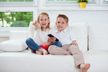 Little brother and sister watching tv on couch