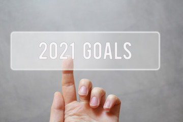 2021 goals - finger pressing grey transparent button on gray virtual touchscreen interface. New year resolutions planning concept.