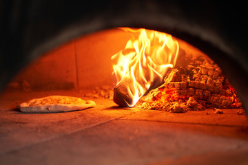 Baked tasty margherita pizza in Traditional wood oven in Naples restaurant, Italy. Original...