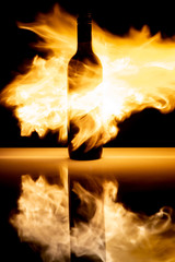 Butelka wina okryta płomieniami ognia, efekt odbicia na stole