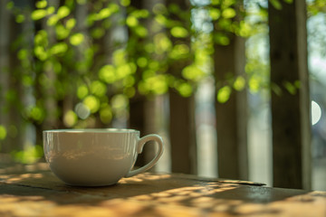 A cup of coffee on a wooden table in the morning. With copy space. and sunlight naturally a blurred background.