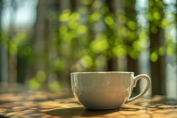 A cup of coffee on a wooden table in the morning. With copy space. and sunlight naturally a blurred background.