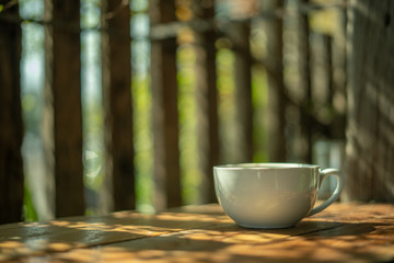 A cup of coffee on a wooden table in the morning. With copy space. and sunlight naturally a blurred background.