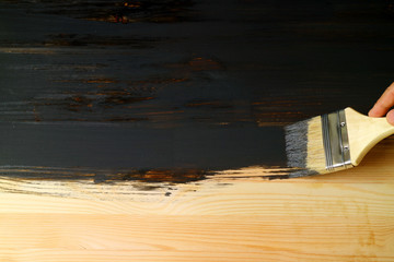 Hand painting the surface of natural wood plank with paintbrush