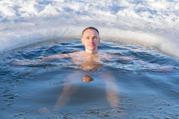 Portrait of a guy swimming in winter in the cold water of a lake, closeup