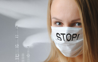 woman in a medical respiratory mask with the inscription stop close-up on a gray background. air pollution and global warming concept