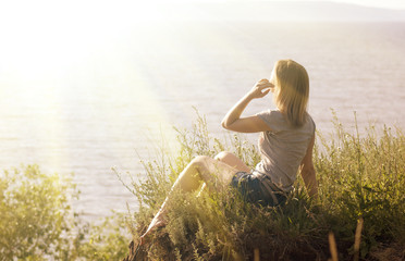 beautiful girl near the sea on a background of fantastic sunset. woman blonde enjoys the warm rays of the sun
