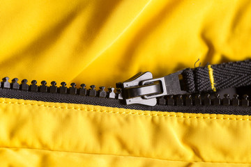 Zipper on clothes close-up. black color. Bright yellow jacket