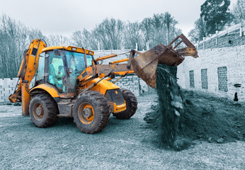 The modern excavator performs excavation work on the construction site. Front view of a digger...