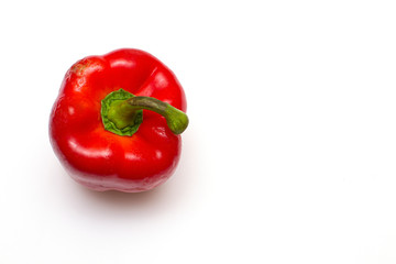 One bright red raw bell pepper with green tail on a white isolated background with a place for recording