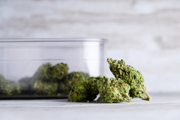 An air sealed container and recreational marijuana flower buds against a white stone background after Illinois passes a law to legalize weed sales and pardon weed related prisoners - obrazy, fototapety, plakaty