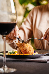 Modern Ukrainian, European cuisine. The girl eats a meatball in Kiev and drinks red wine in a restaurant. In the hands of a knife and fork. background image, copy space text