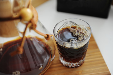 Filter pour-over coffee served in crystal glass and decanter on bamboo board. Third wave specialty aesthetics