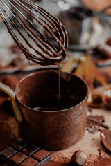 Process of preparation of delicious homemade dark chocolate. Whisk mixer, vintage copper tableware, ingredients on the table. Gourmet dessert. Close up, macro