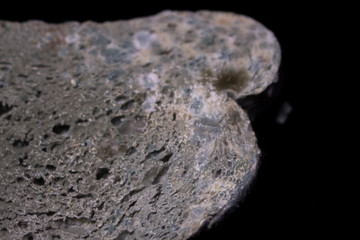 Moldy white bread on a black background.  Slice of moldy bread on a black table
